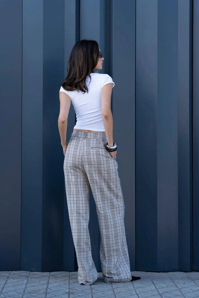 Vue arrière d'une femme en tailleur pantalon à carreaux beige look structuré, mettant en valeur le style contemporaine et les poches pratiques. Pantalon femme carreaux.