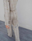 Vue arrière d'une femme en tailleur pantalon à carreaux beige look structuré, montrant la silhouette stylée et la coupe fluide, idéale pour un style chic. Pantalon femme carreaux.