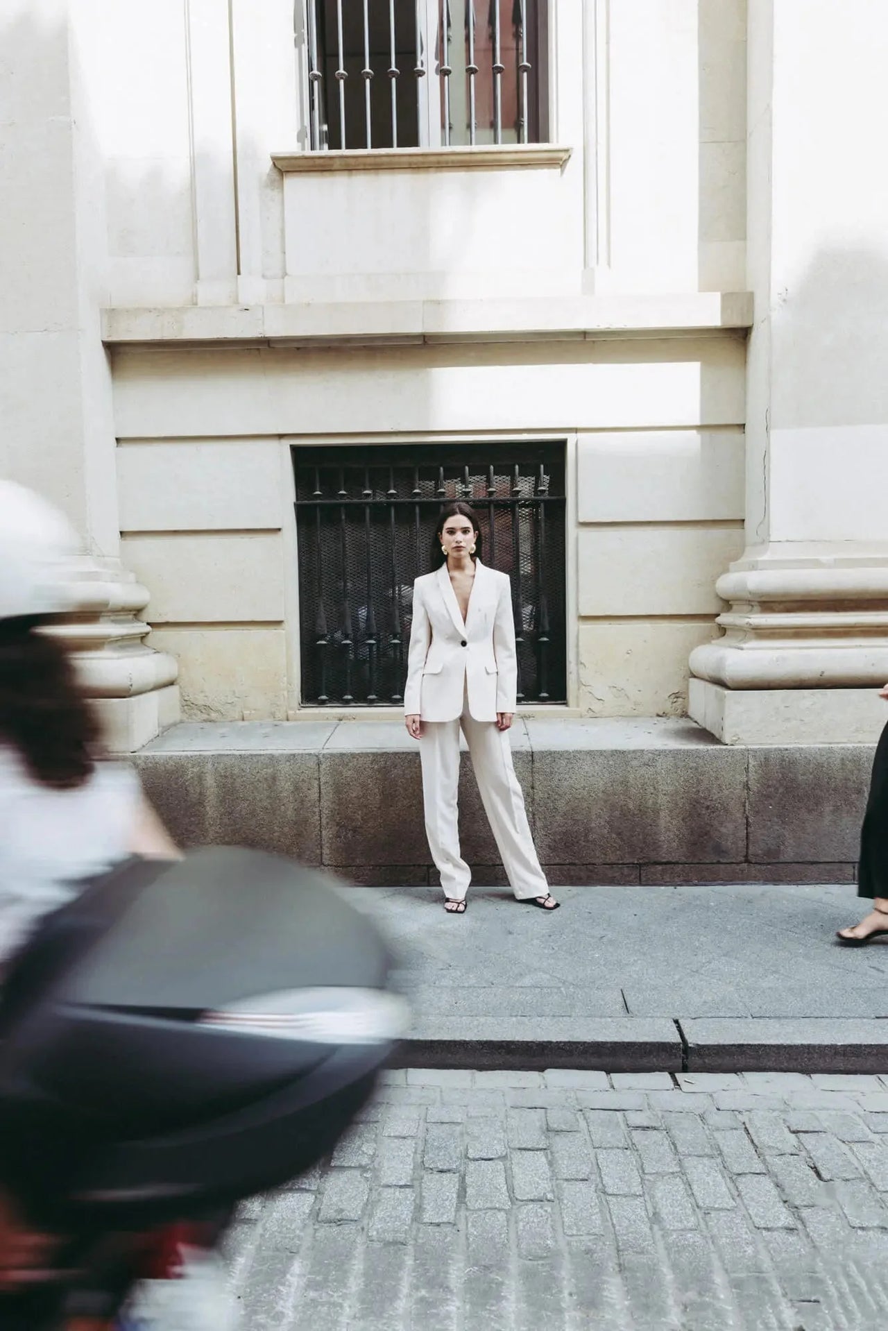 Femme en tailleur pantalon ample crème se tenant droite, arborant un style chic, parfait pour un pantalon pince femme.