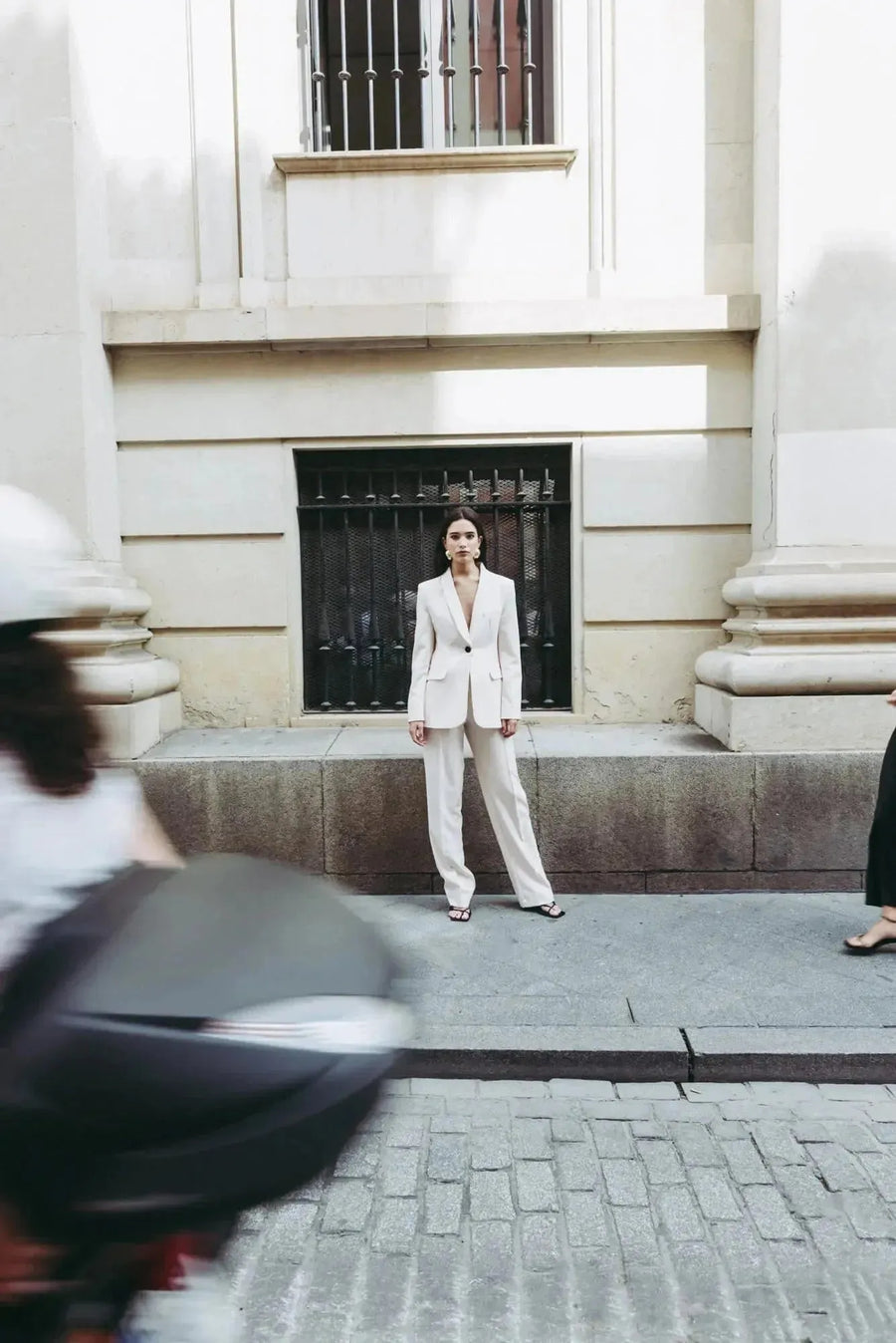 Femme en tailleur pantalon ample crème se tenant droite, arborant un style chic, parfait pour un pantalon pince femme.