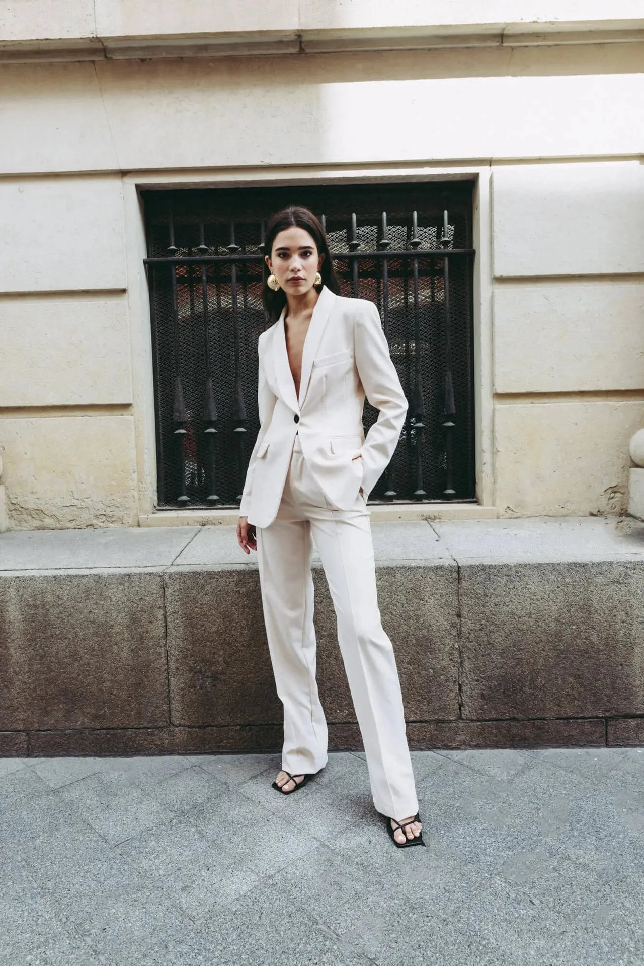 Femme s'affichant dans un tailleur pantalon ample crème, illustrant le confort et l'élégance du pantalon pince femme.
