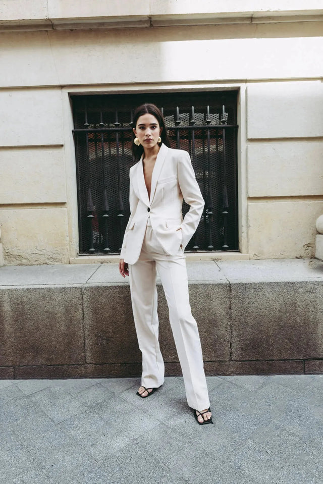 Femme s'affichant dans un tailleur pantalon ample crème, illustrant le confort et l'élégance du pantalon pince femme.