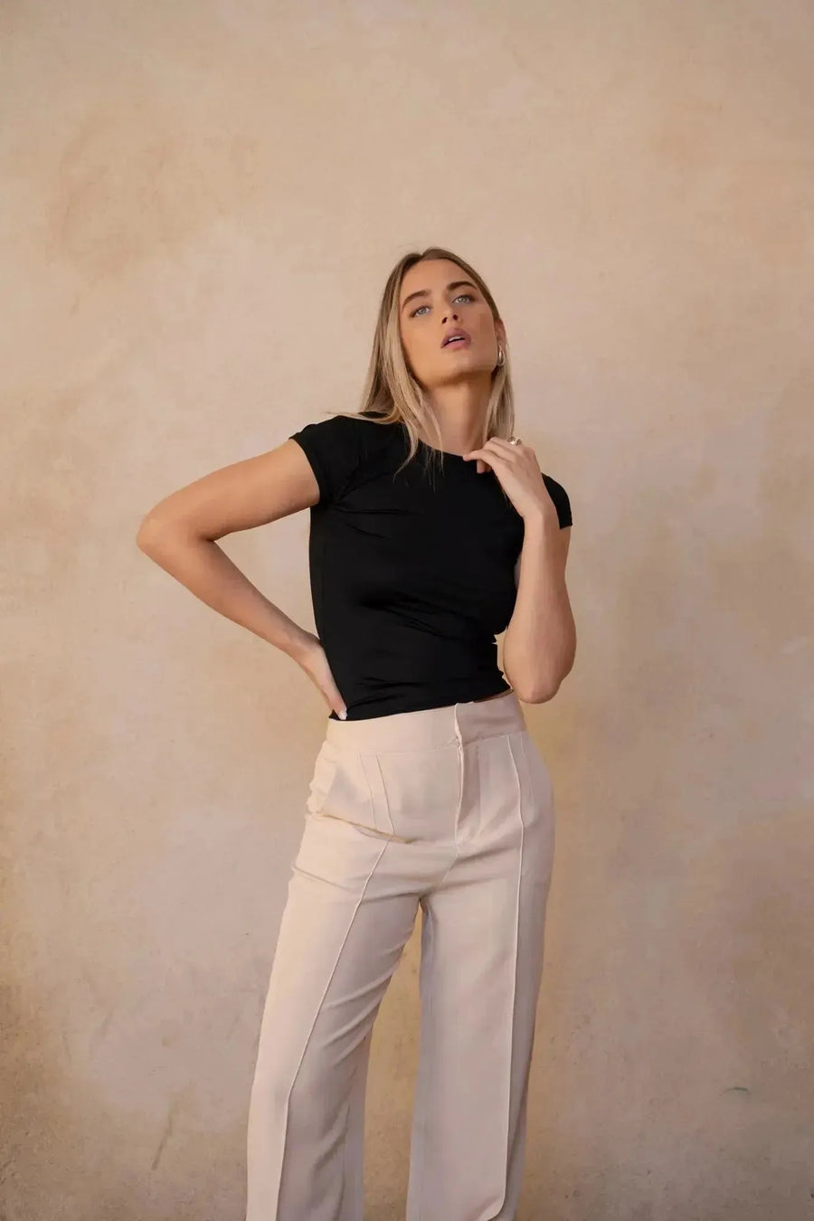 Modèle féminin adoptant une pose confiante dans un tailleur crème, soulignant le style moderne du pantalon pince femme.