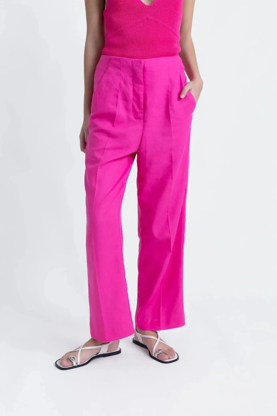 Détail d'un pantalon femme mode lin rose fuchsia taille haute fluide, porté avec des sandales modernes.