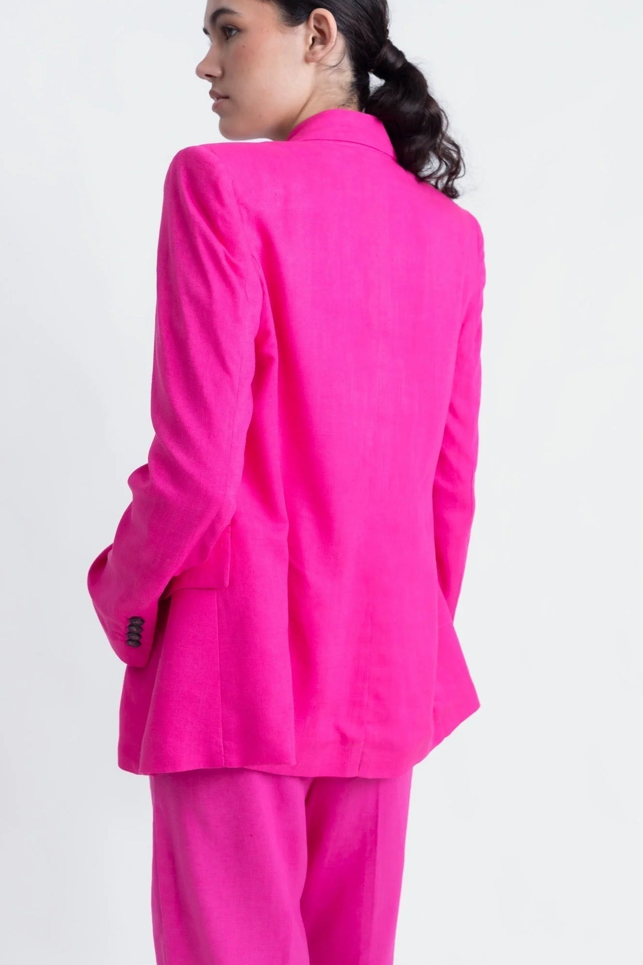 Détail sur le dos d'un tailleur pantalon en lin rose fuchsia, blazer rose fuchsia femme, avec coupe raffinée.