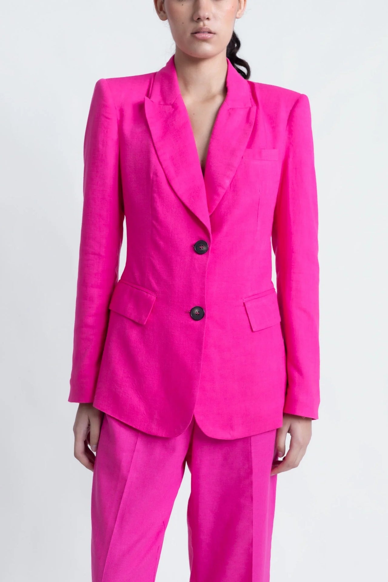 Zoom sur un tailleur pantalon en lin rose fuchsia, blazer rose fuchsia femme, coupe cintrée.