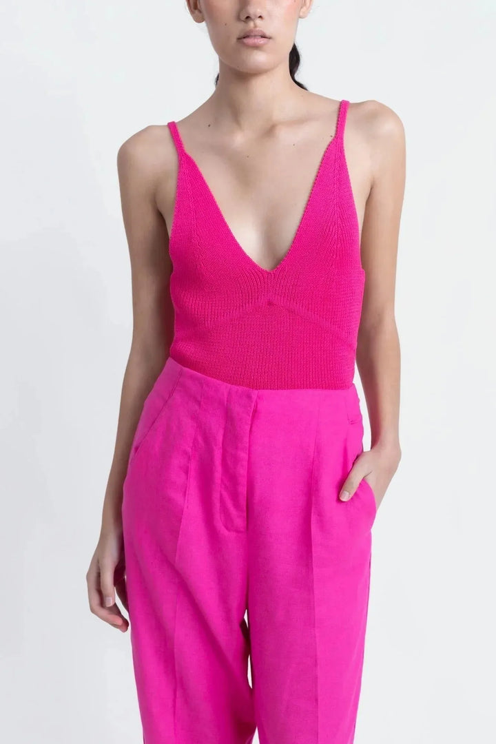 Femme portant un pantalon femme mode lin rose fuchsia taille haute fluide élégant et confortable, combinaison avec un top en maille fuchsia.