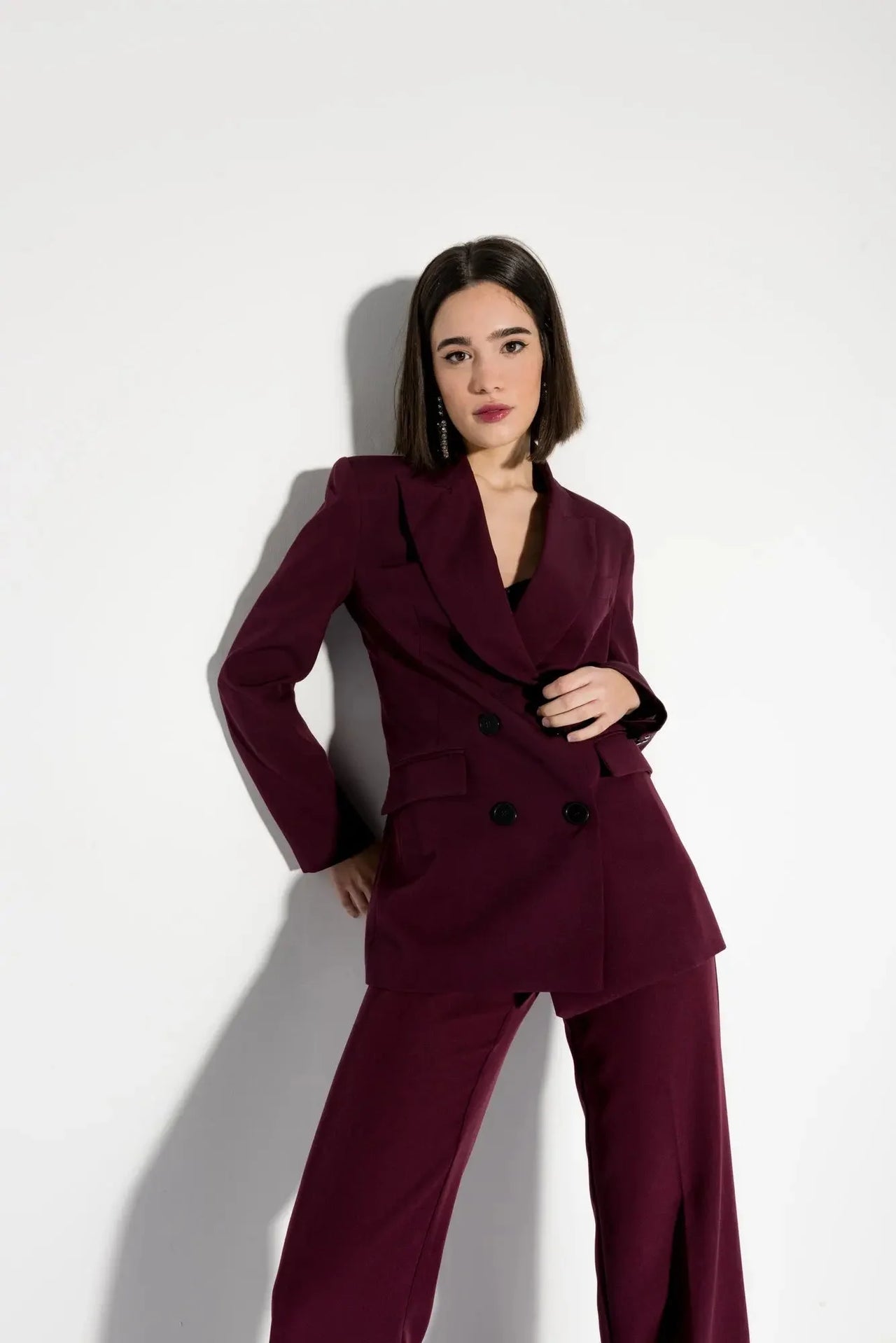 La model dans un blazer femme bordeaux double boutonnage croisé, montrant une allure élégante en pose.