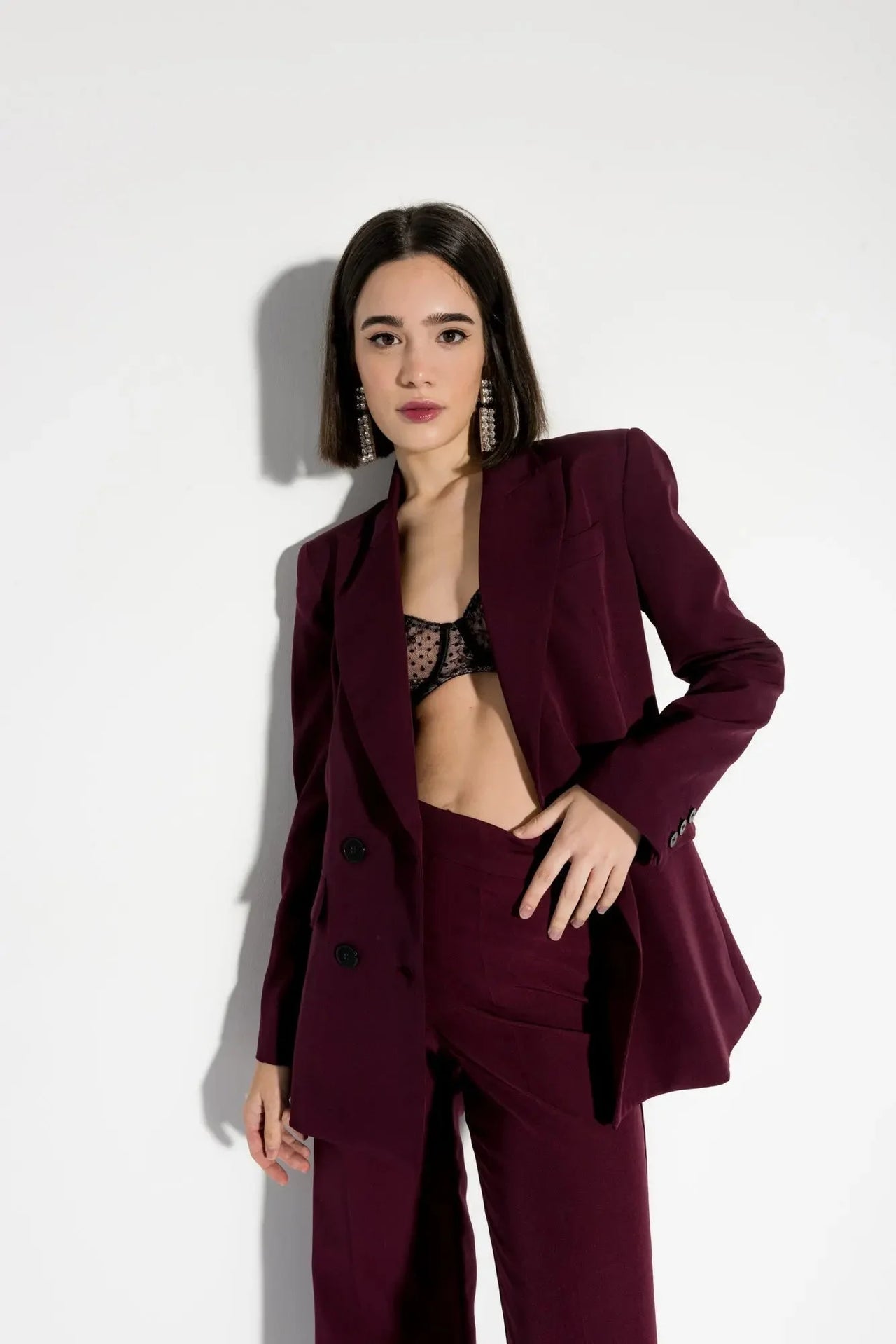 Modèle portant un blazer femme bordeaux double boutonnage croisé, avec un pantalon assorti, chic et moderne.