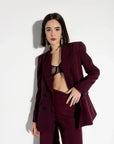 Modèle portant un blazer femme bordeaux double boutonnage croisé, avec un pantalon assorti, chic et moderne.