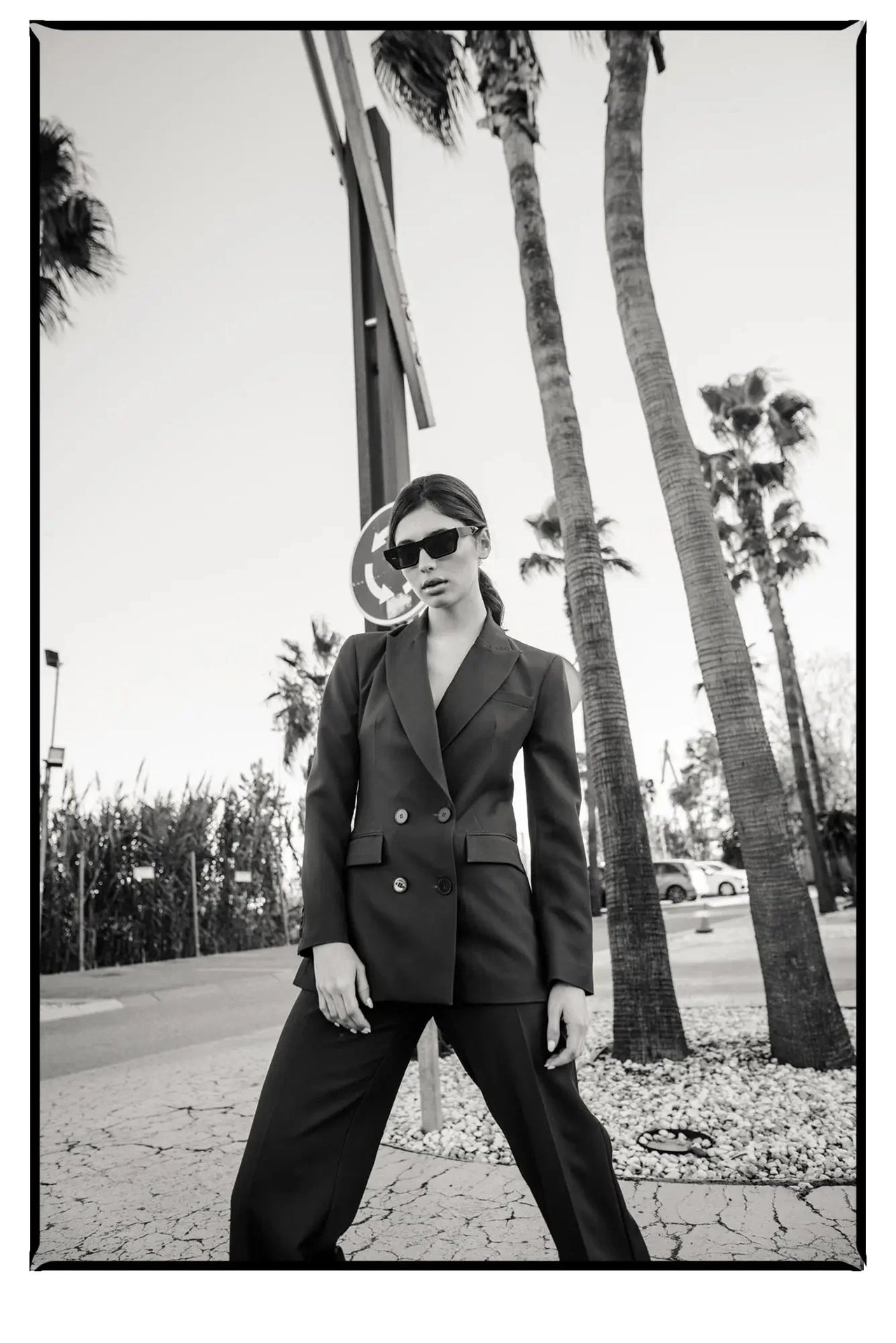 Portrait d'une femme en extérieur, arborant un blazer femme bordeaux double boutonnage croisé, lunettes de soleil, affichant une allure sophistiquée.