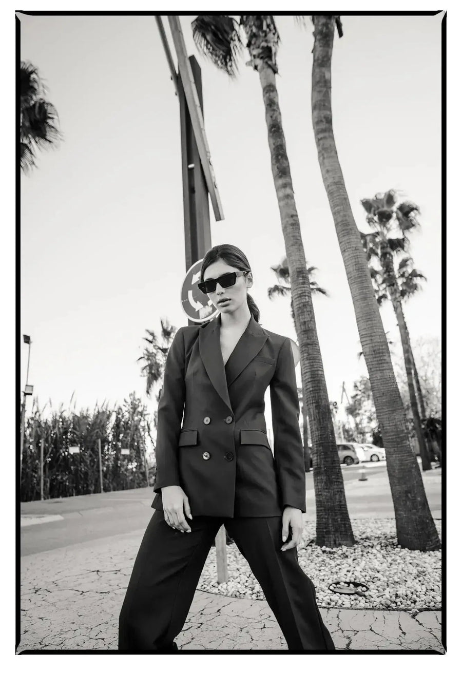 Portrait d'une femme en extérieur, arborant un blazer femme bordeaux double boutonnage croisé, lunettes de soleil, affichant une allure sophistiquée.