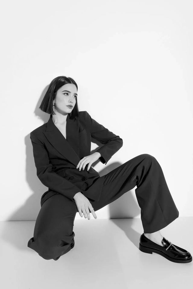 Femme photographiée en noir et blanc, vêtue d'un blazer femme bordeaux double boutonnage, affichant une mode contemporaine.