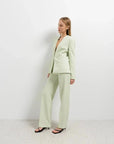 Femme posant dans un pantalon vert femme droit et chic, mettant en avant le look élégant et confortable de la marque Sapiato.