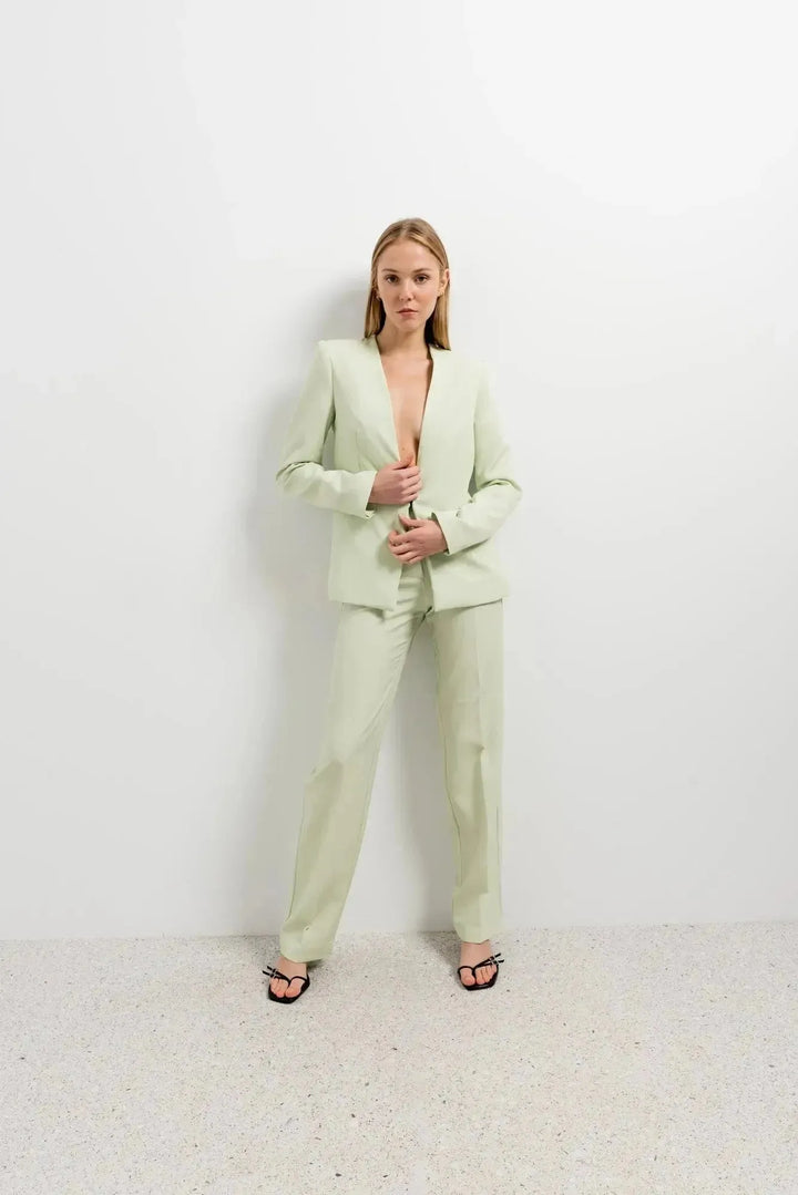 Femme en pantalon vert femme et blazer, saisissant l'attention avec son style moderne et tendance dans une ambiance lumineuse.