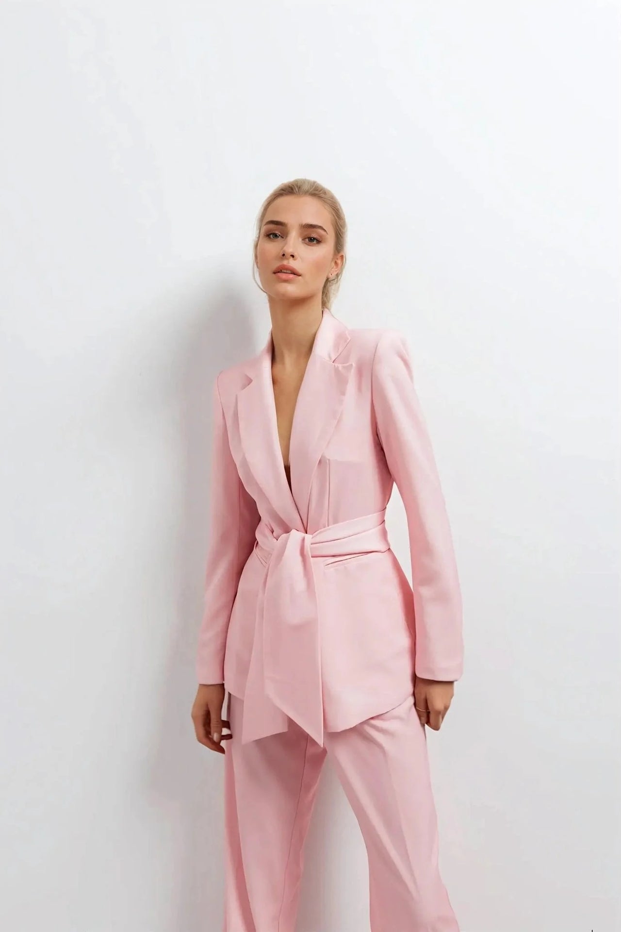 Pantalon rose femme ceinturé pour toutes occasions, une femme en pose élégante avec un blazer rose, idéale pour un look tendance.
