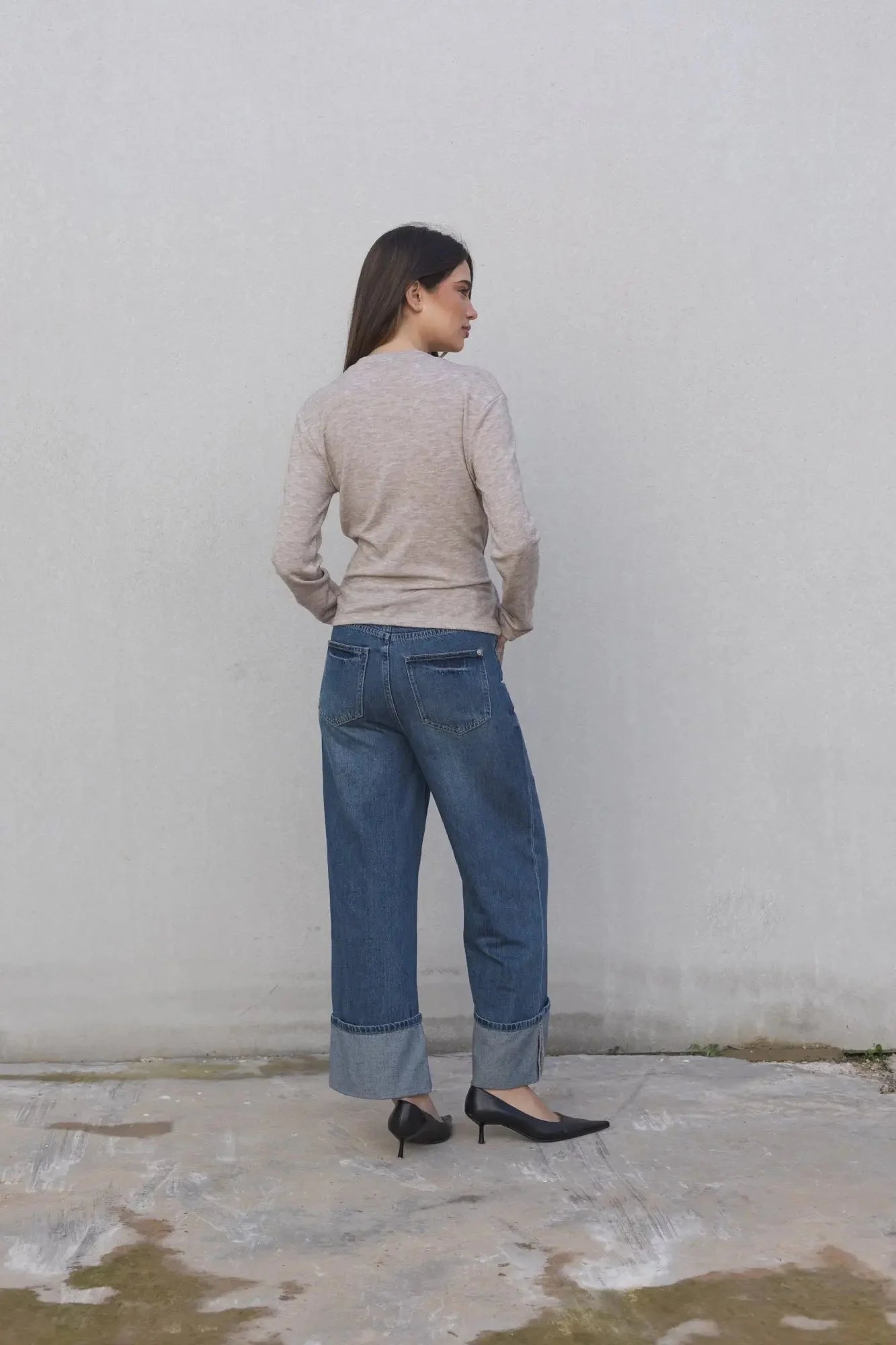 Vue arrière d'une femme dans un tee shirt beige femme à nouer manches longues avec un jean, affichant un look tendance et contemporain.