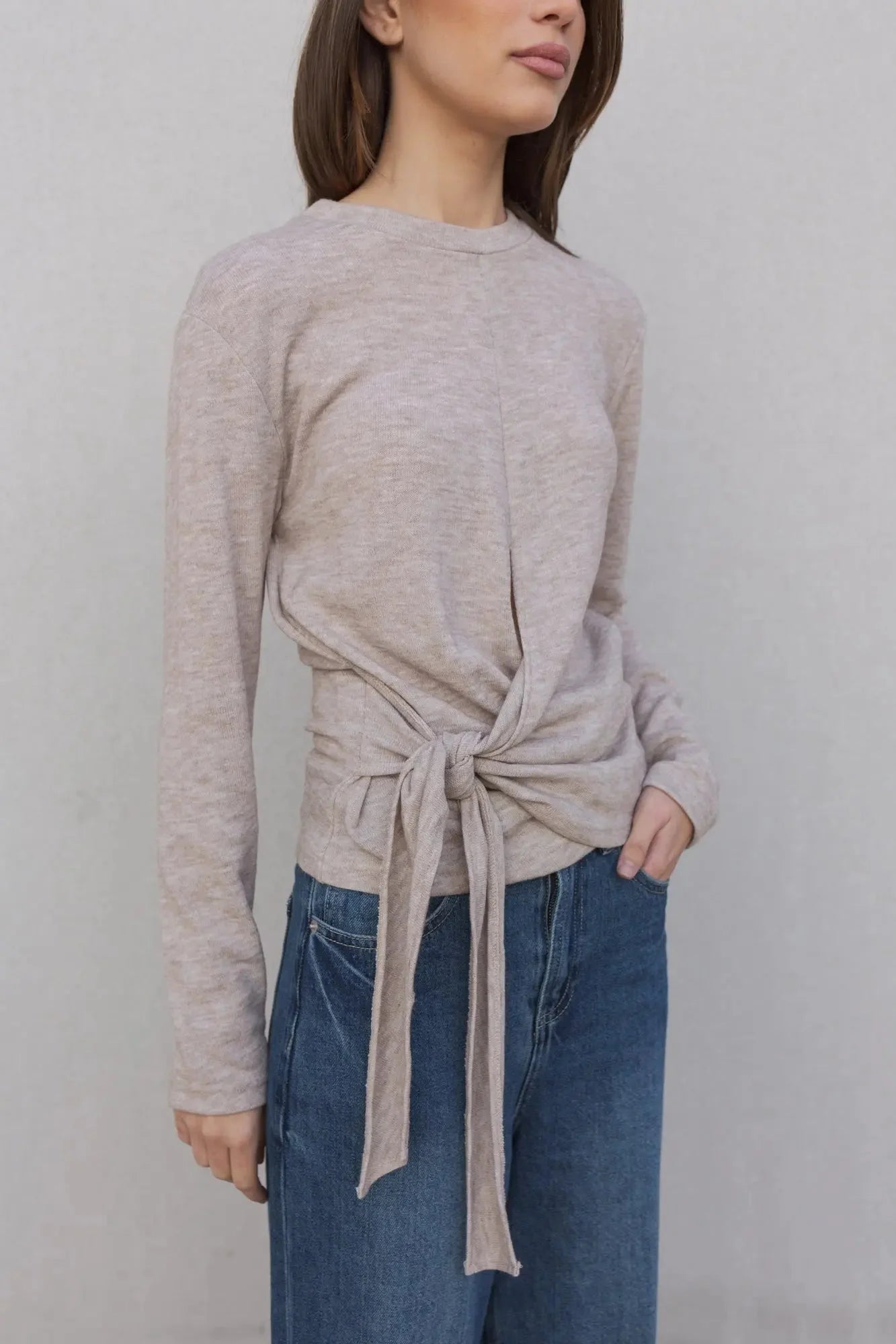 Détail du tee shirt beige femme à nouer manches longues, mettant en avant le nœud et le tissu doux, parfait pour un look chic et confortable.