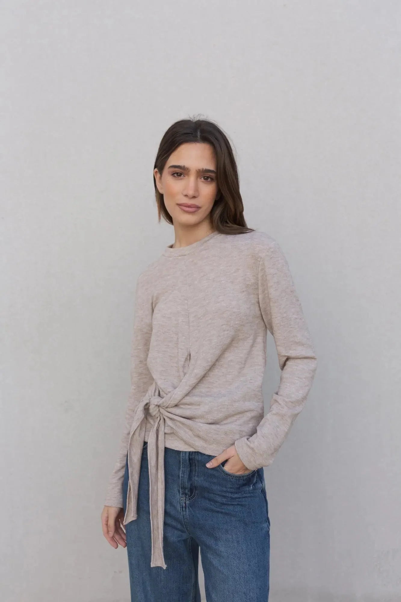 Tee shirt beige femme à nouer manches longues, élégant et confortable pour toutes les occasions, porté par une femme avec un style décontracté.