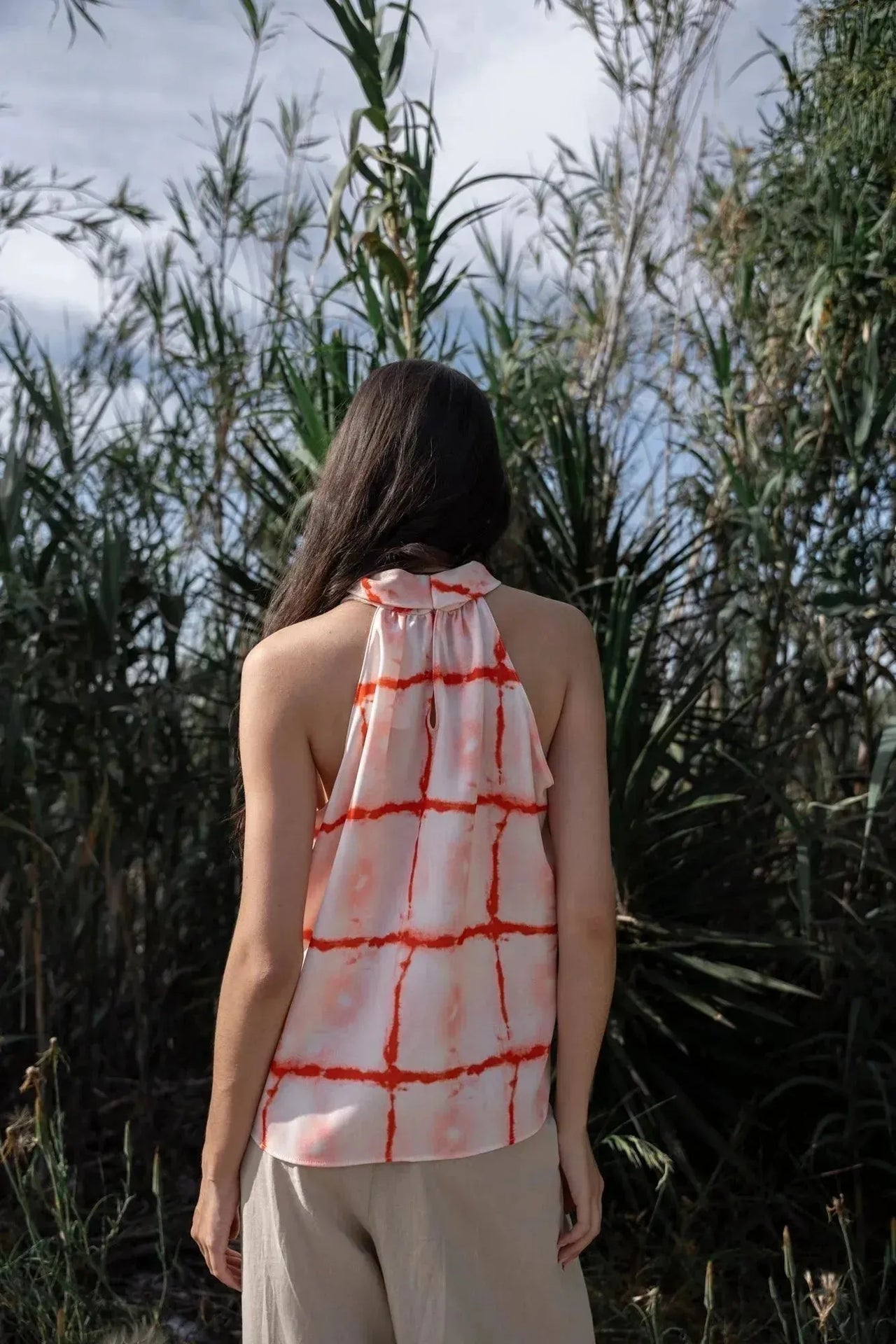 Vue arrière d'un modèle portant le Top Col Halter Imprimé Graphique Rouge Et Blanc, mettant en lumière le col noué et l'imprimé graphique.