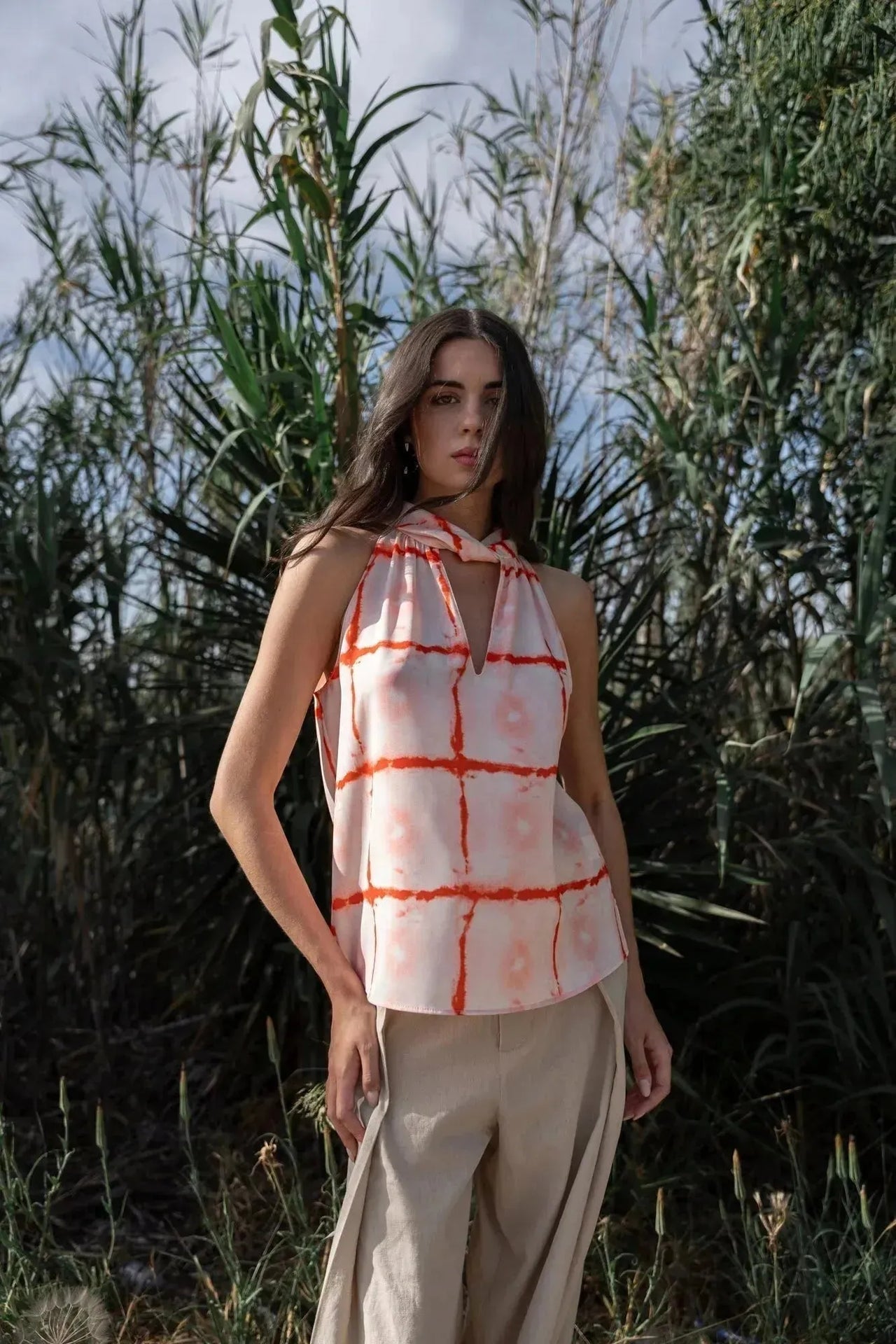 Modèle portant le Top Col Halter Imprimé Graphique Rouge Et Blanc Avec Motif Quadrillage, en pleine nature, mettant en valeur le col haut et l'imprimé audacieux.