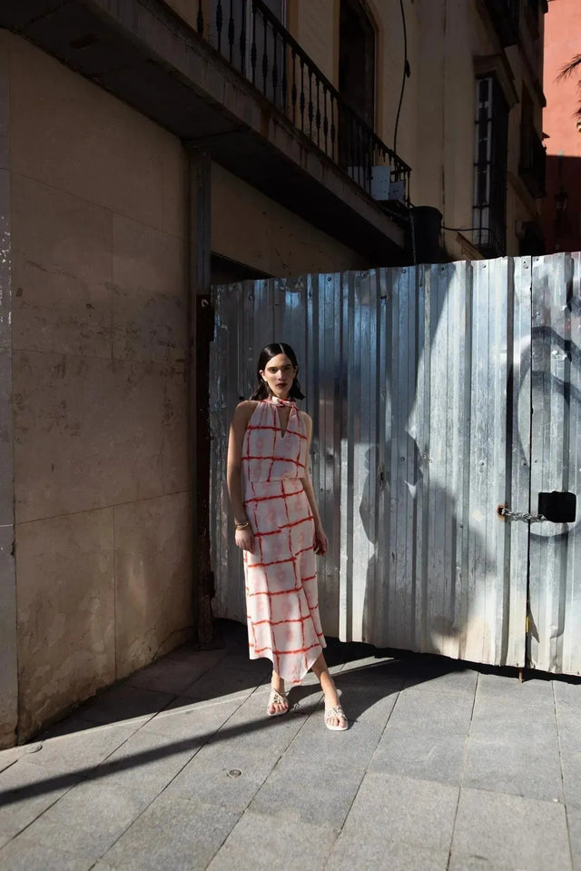 Femme posant avec le Top Col Halter Imprimé Graphique Rouge Et Blanc devant une porte métallique, montrant le design moderne et élégant.