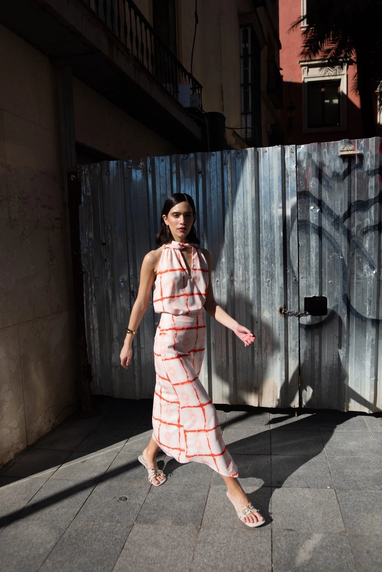 Femme portant un top à motifs géométriques rouge avec col noué et coupe fluide