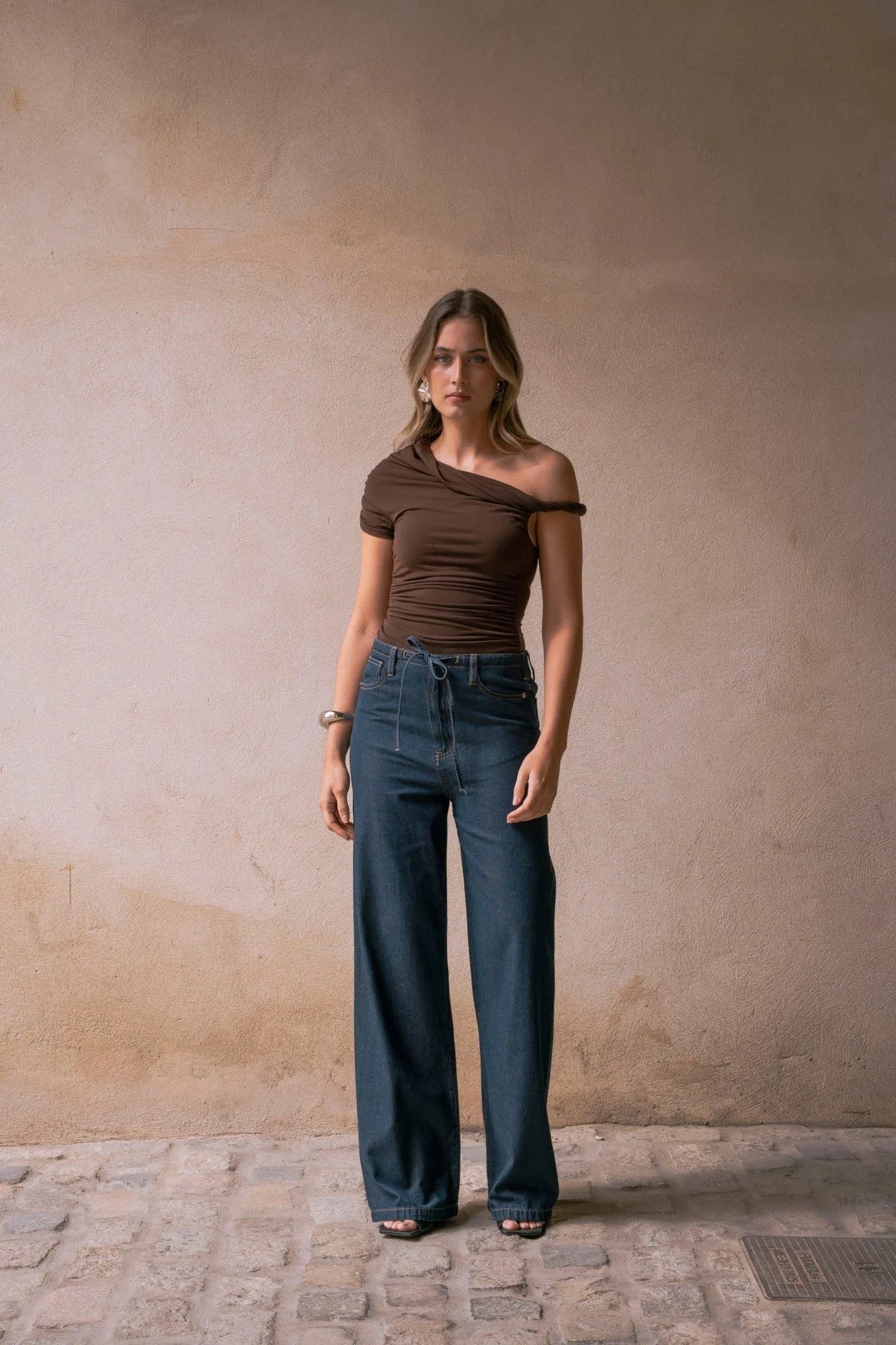 Femme portant un top asymétrique marron au design unique et look décontracté