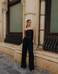 Modèle posant en extérieur avec un top bandeau femme noir élégant, mettant en valeur un top paillette noir et un pantalon noir large.