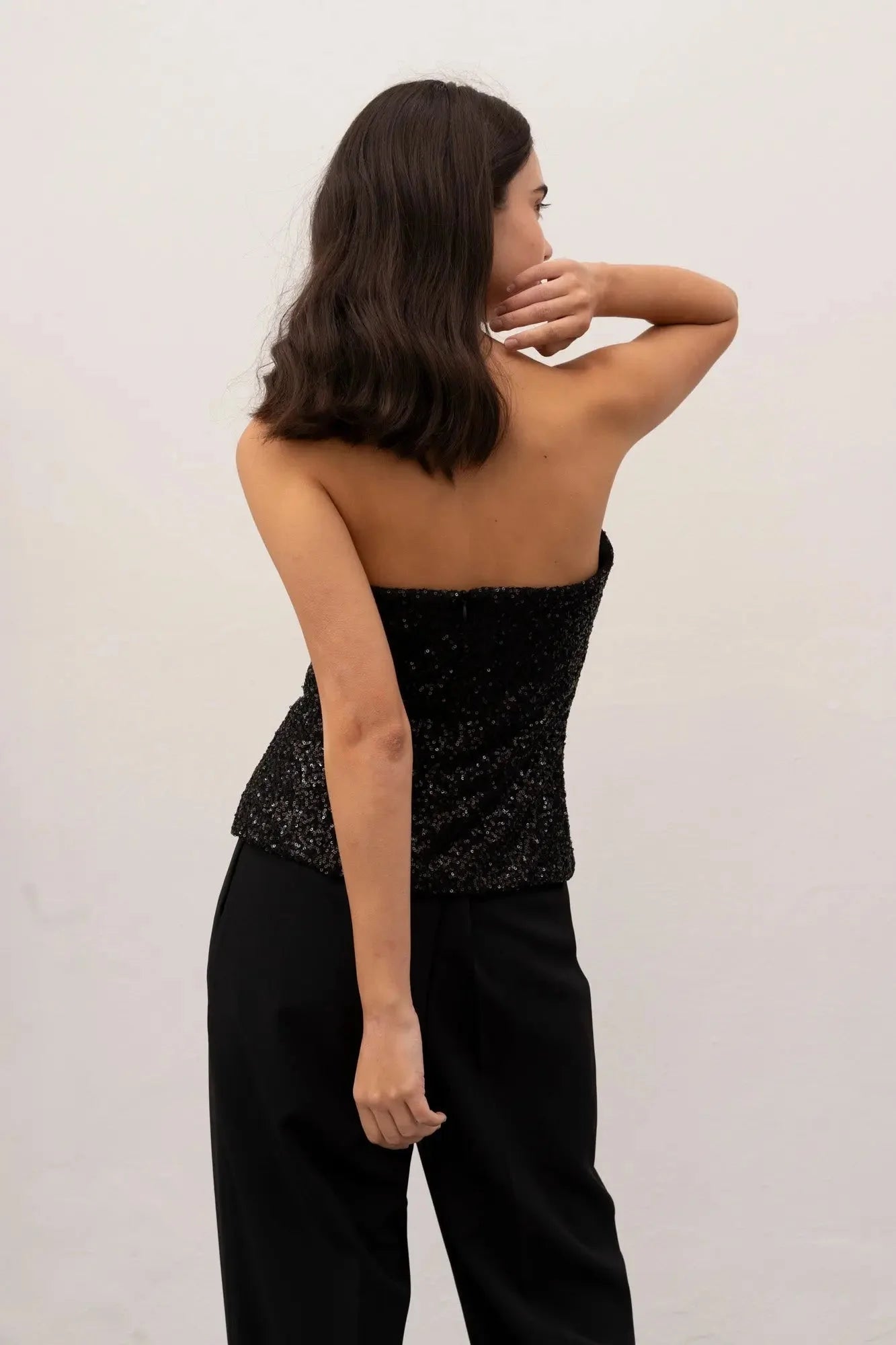 Femme portant un top bandeau femme noir élégant en sequins et pantalon noir