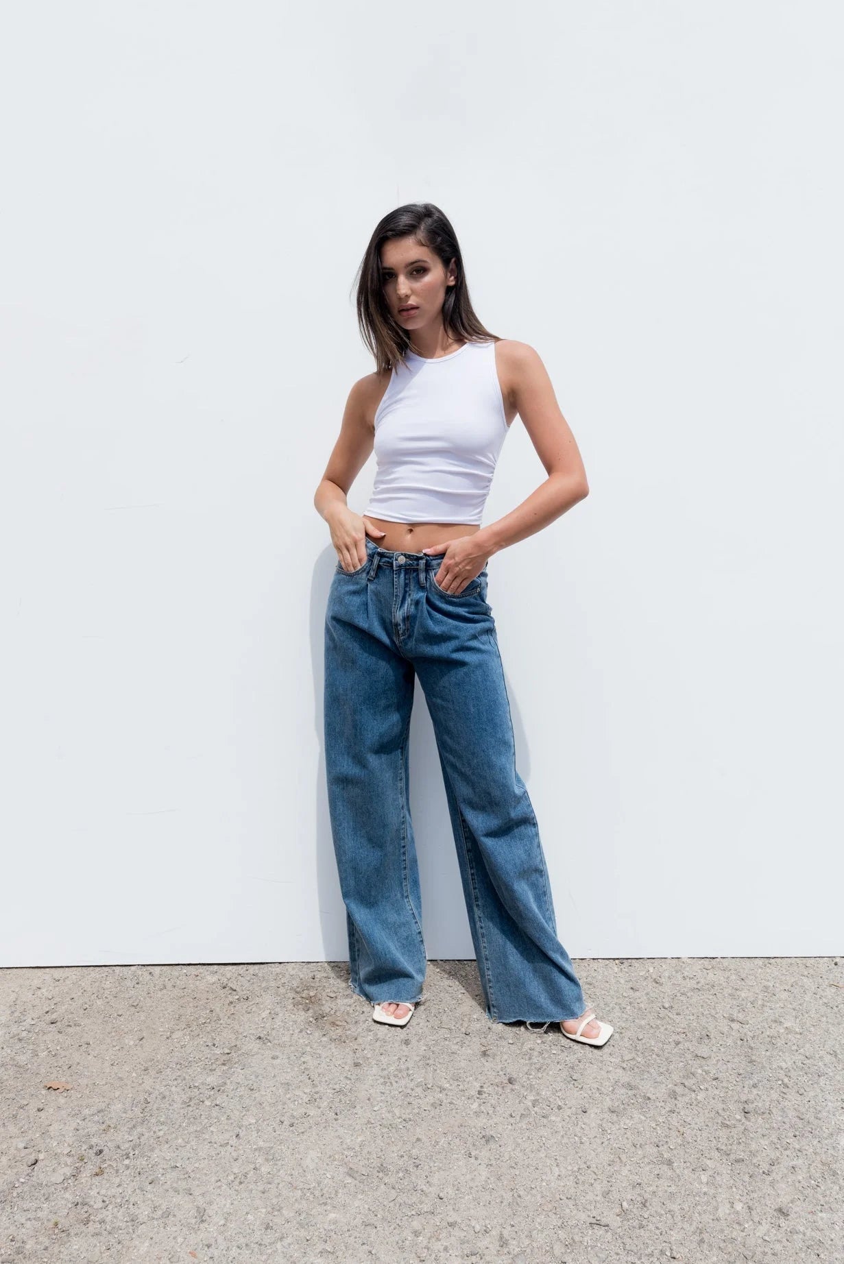 Femme portant un haut blanc moulant sans manches en coton stretch et jeans bleus