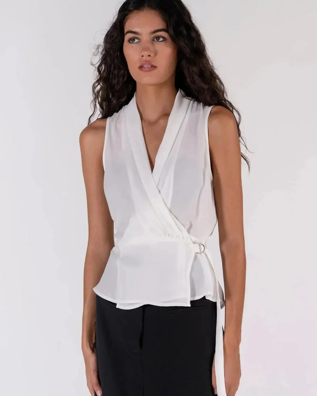 Détail du haut blanc croisé sans manches avec un nœud sur le côté, un ajout chic à la garde-robe des hauts blancs femme.