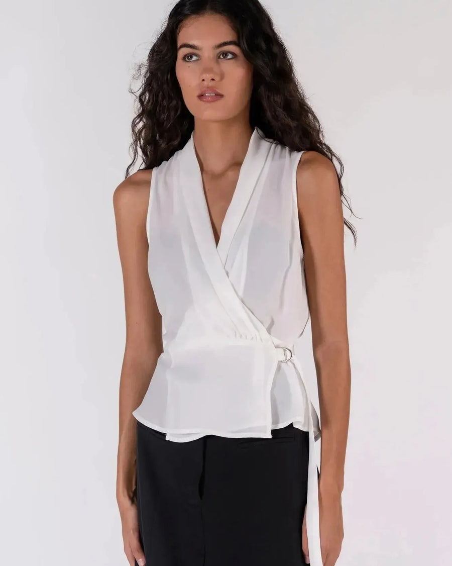 Détail du haut blanc croisé sans manches avec un nœud sur le côté, un ajout chic à la garde-robe des hauts blancs femme.