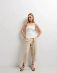 Top bustier péplum blanc sans bretelles, associé à un pantalon beige, mettant en avant la féminité et le confort.