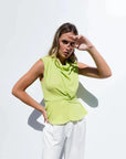 Modèle en haut col bénitier noué vert lime, affichant une allure élégante avec un pantalon blanc. Idéal pour les sorties décontractées. Haut col bénitier femme.