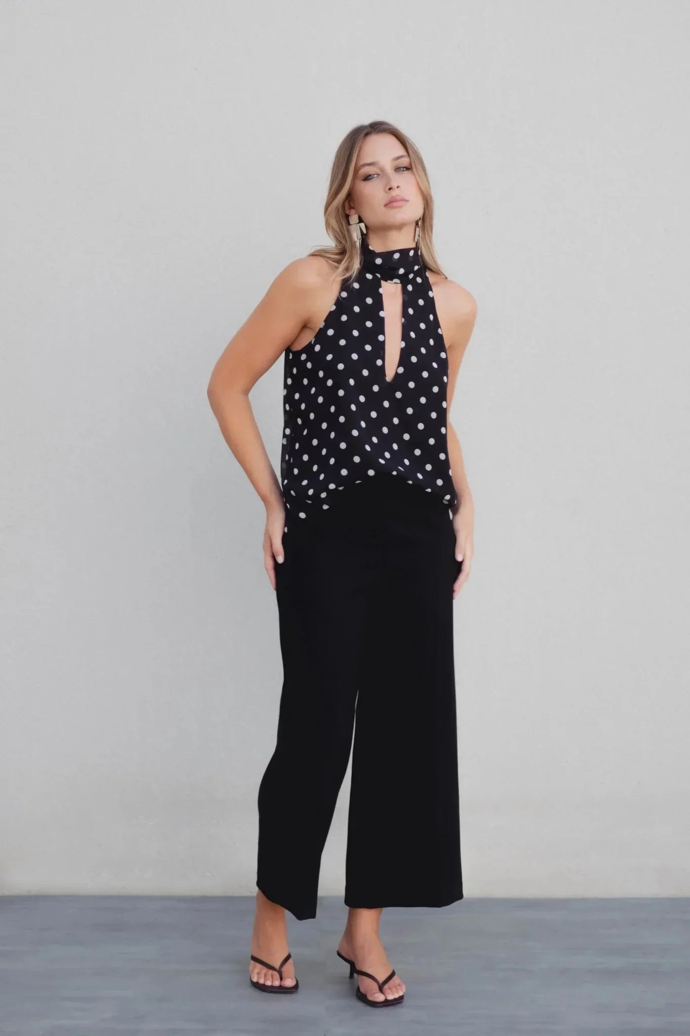 Top col montant noir à pois blancs avec décolleté en V et coupe élégante