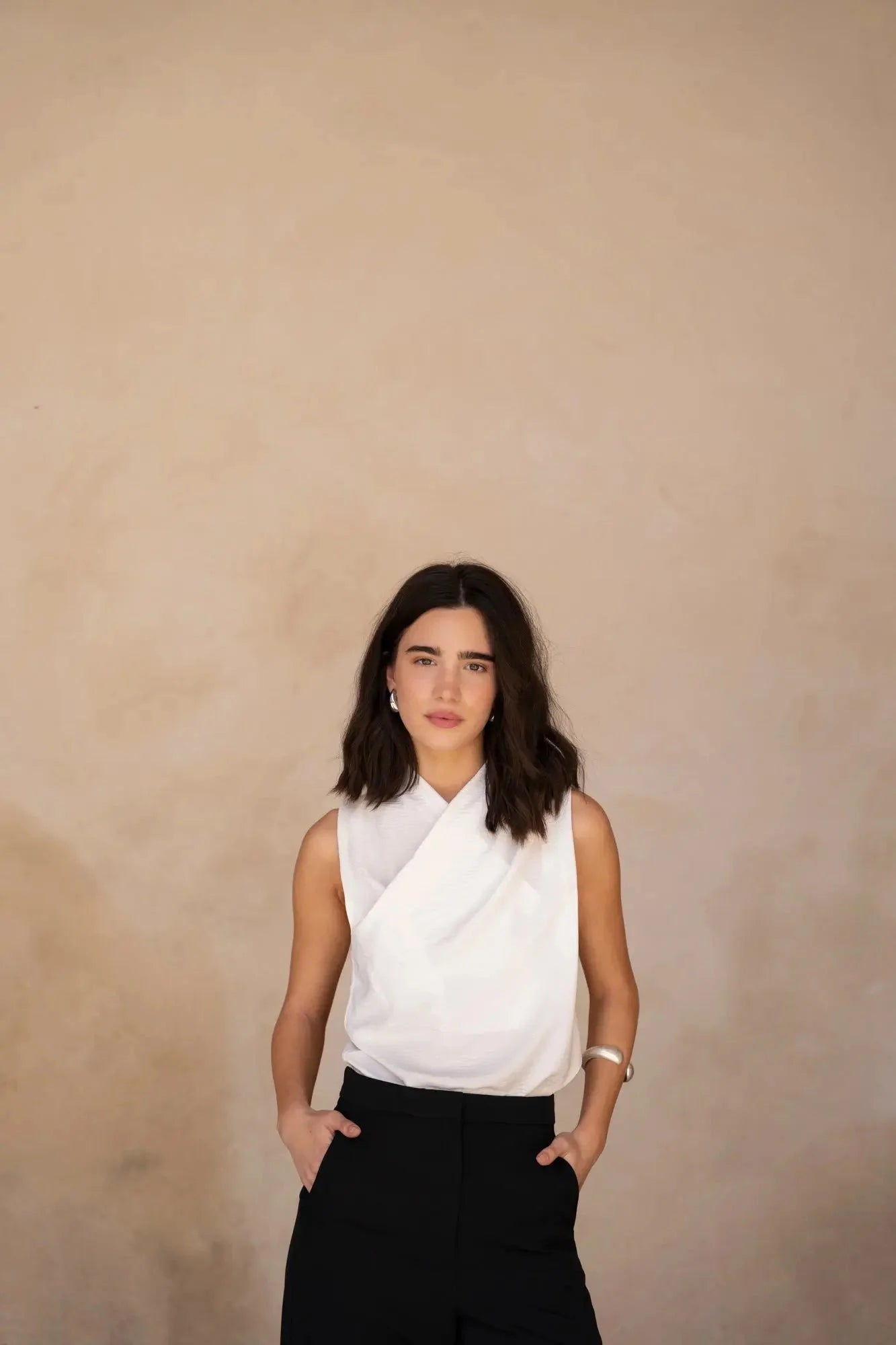 Femme avec un regard confiant, portant le Top Croisé Devant Blanc Chic, les mains dans les poches.