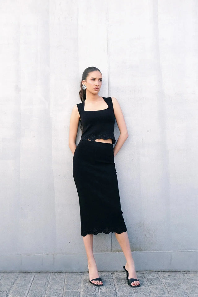 Top élégant soirée – Style minimaliste ajusté – Noir – Encolure carrée, modèle se tenant debout avec une jupe, soulignant le style chic.