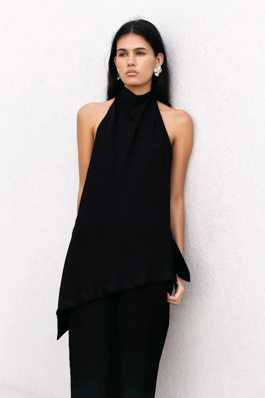Top halter noir et pantalon assorti porté par une femme, mettant en avant un style moderne et élégant. Ce haut long femme à col montant est idéal pour une tenue sophistiquée.