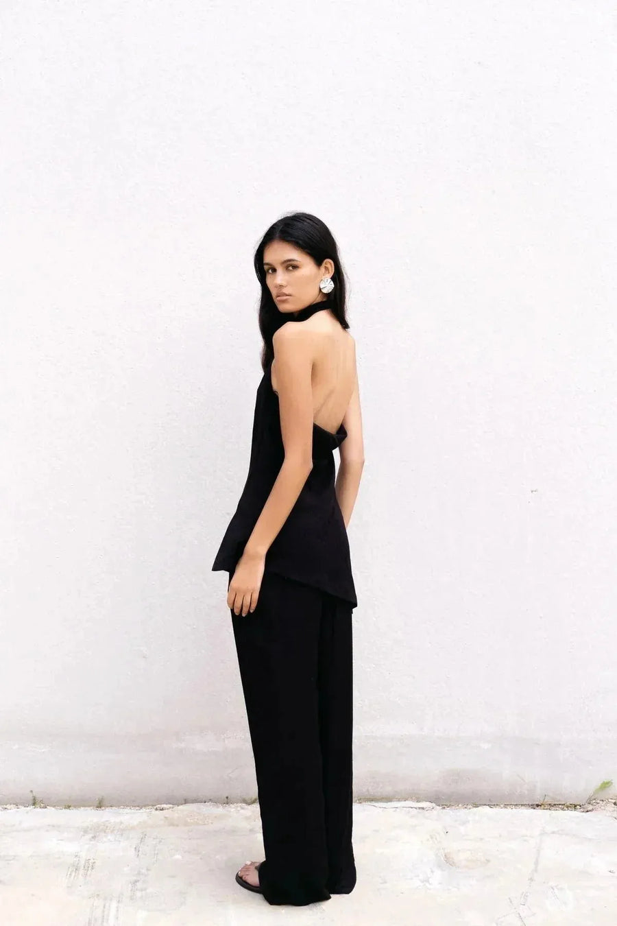 Femme posant avec le haut halter noir et pantalon assorti, rayonnant d'élégance. Ce haut long femme apporte une touche de sophistication à n'importe quelle tenue.