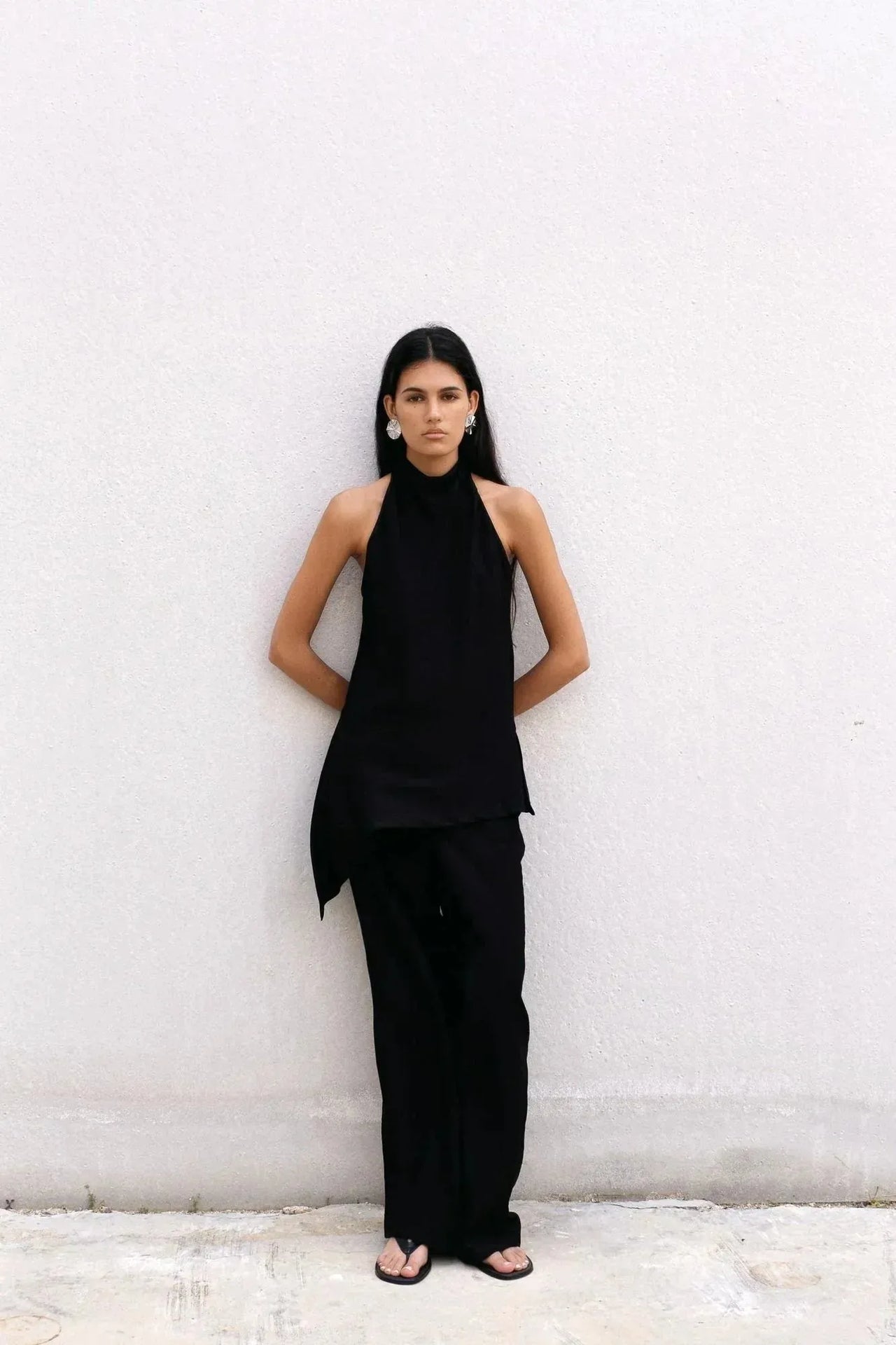 Portrait d'une femme en haut halter noir et pantalon assorti, soulignant le style minimaliste et moderne de ce haut long femme, parfait pour une sortie élégante.