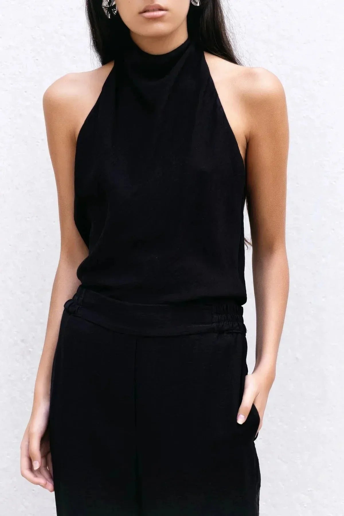 Détail du top halter noir et pantalon assorti, mettant en valeur la coupe fluide et le col montant. Un incontournable pour un haut long femme chic.