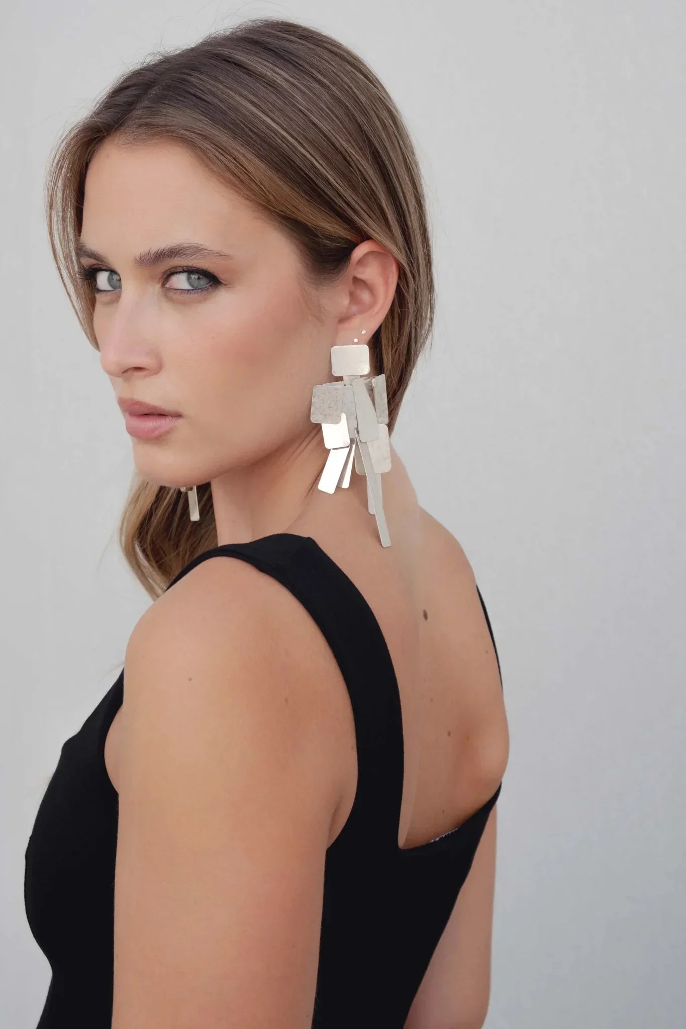 Femme portant un top noir extensible à encolure ronde avec boucles d’oreilles géométriques