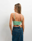 Vue arrière d'une femme dans un crop top vichy vert à bretelles fines, mettant en avant le design ajusté avec jupe en denim.