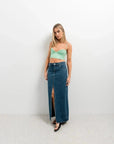 Femme posant dans un crop top vichy vert à bretelles fines et une jupe en denim fendue, look tendance et décontracté.