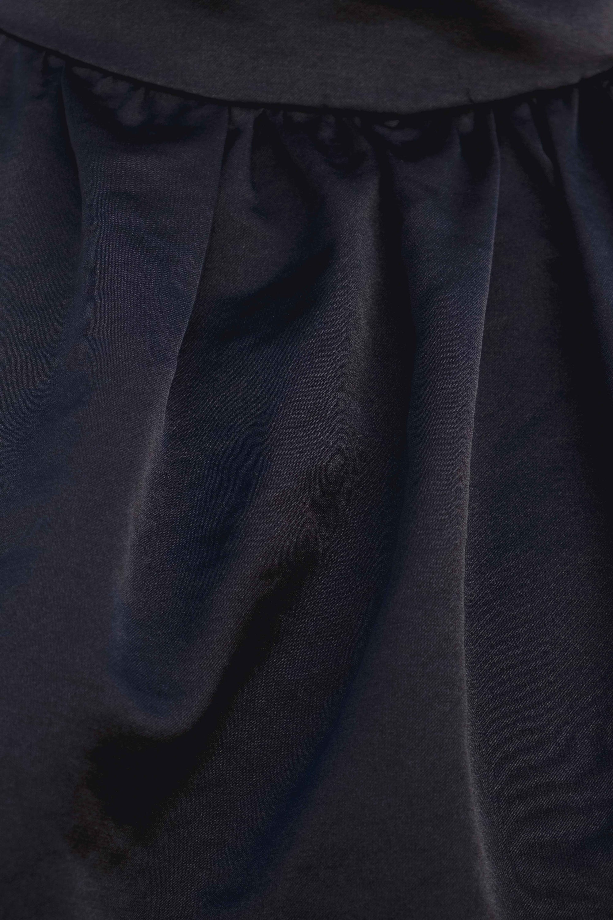 Zoom sur le tissu du top dos nu élégant – Col halter – Noir – Satin, mettant en avant la finition satinée et la coupe.