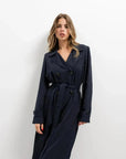 Modèle portant un trench coat femme ample long ceinturé élégant avec poches pratiques, affichant un look moderne.