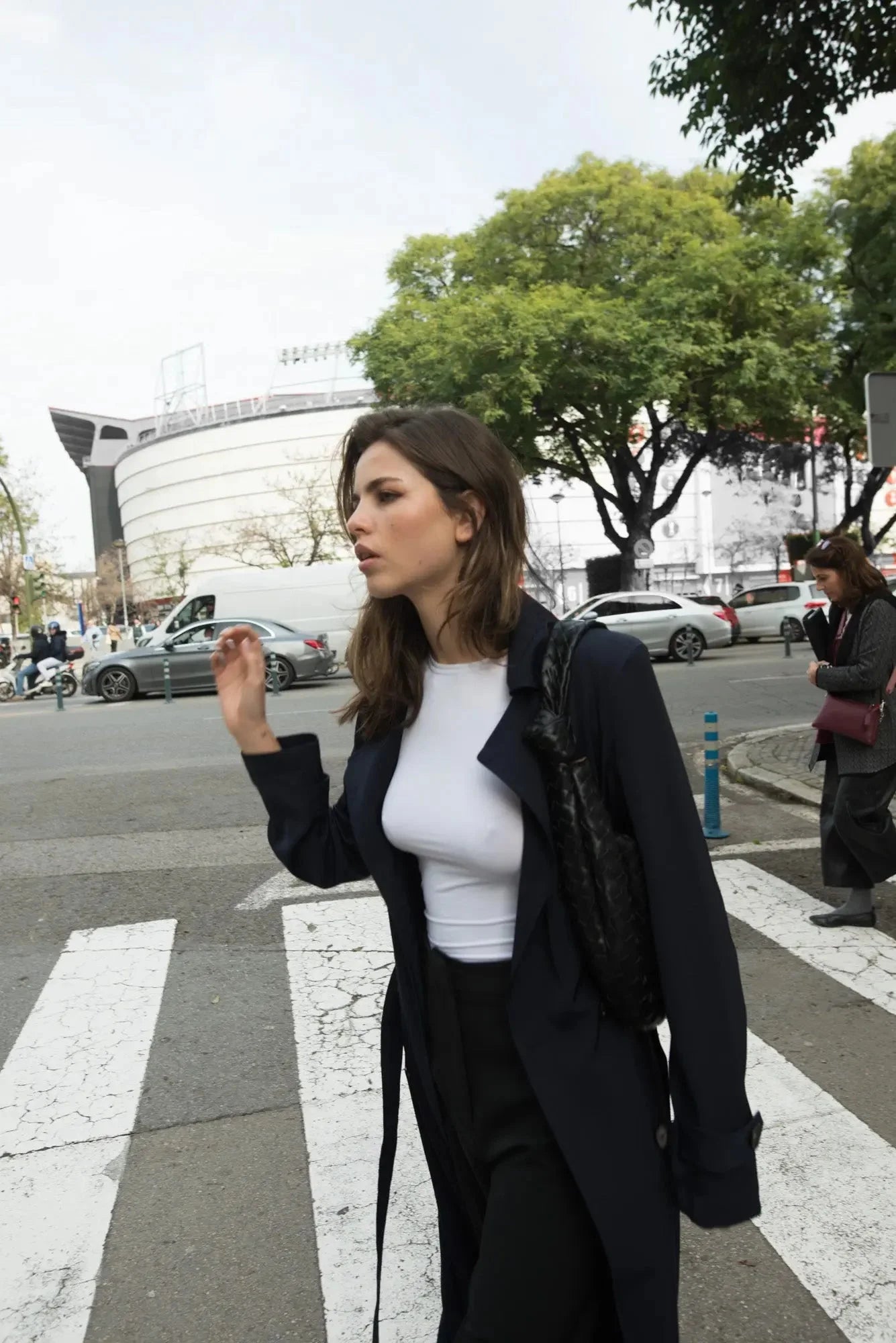 Femme portant un trench-coat ample avec ceinture en traversant la rue