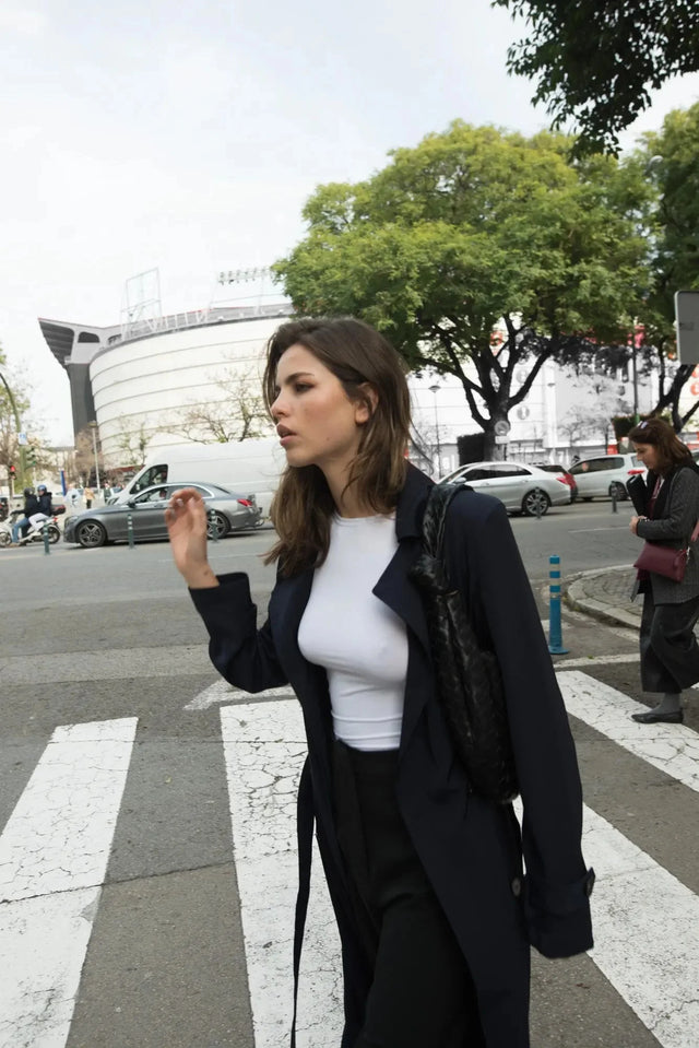 Femme marchant dans la rue portant un trench coat femme ample long ceinturé, combiné avec une tenue décontractée.