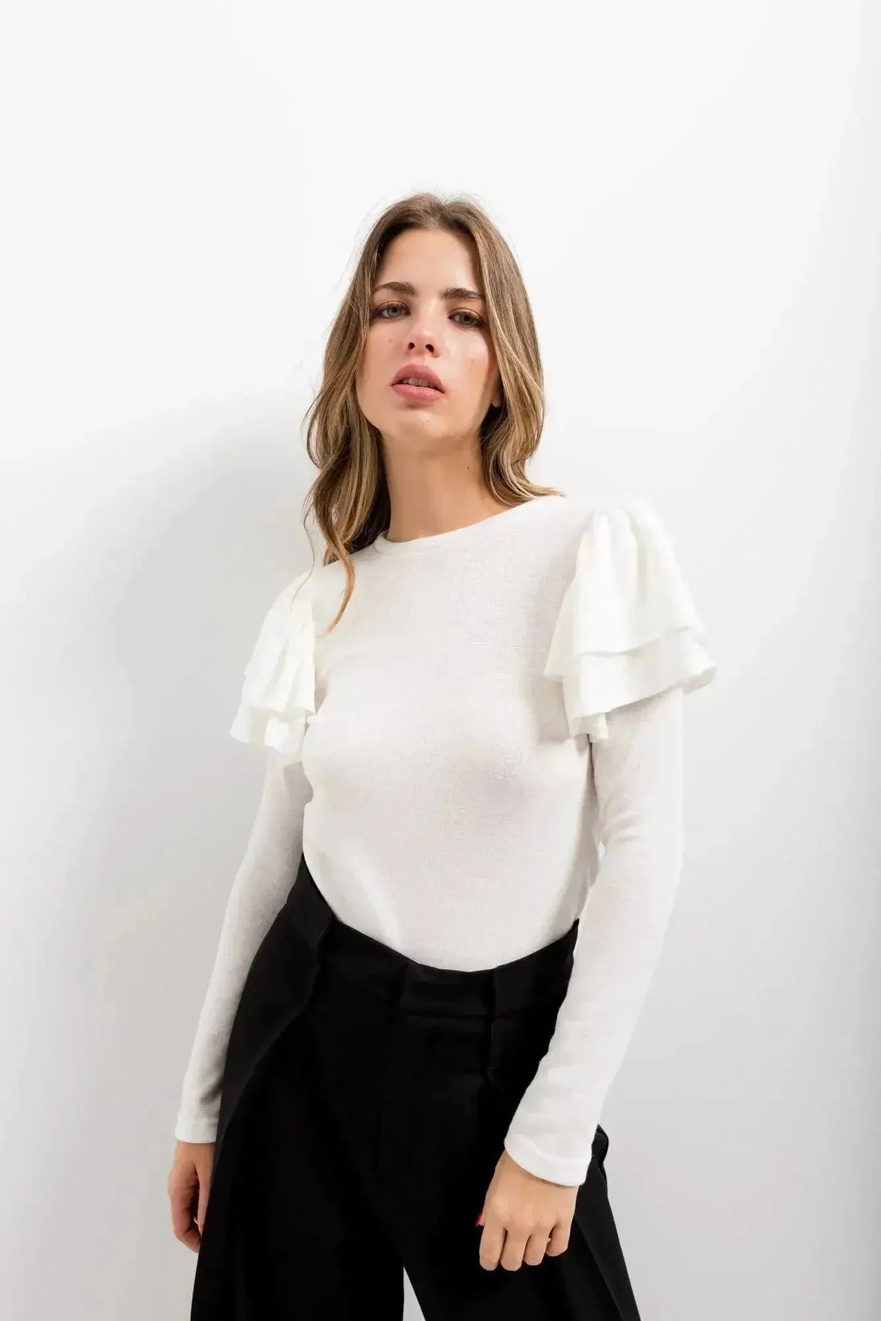 Tricot à volants sur les épaules : femme portant un haut blanc à manches longues